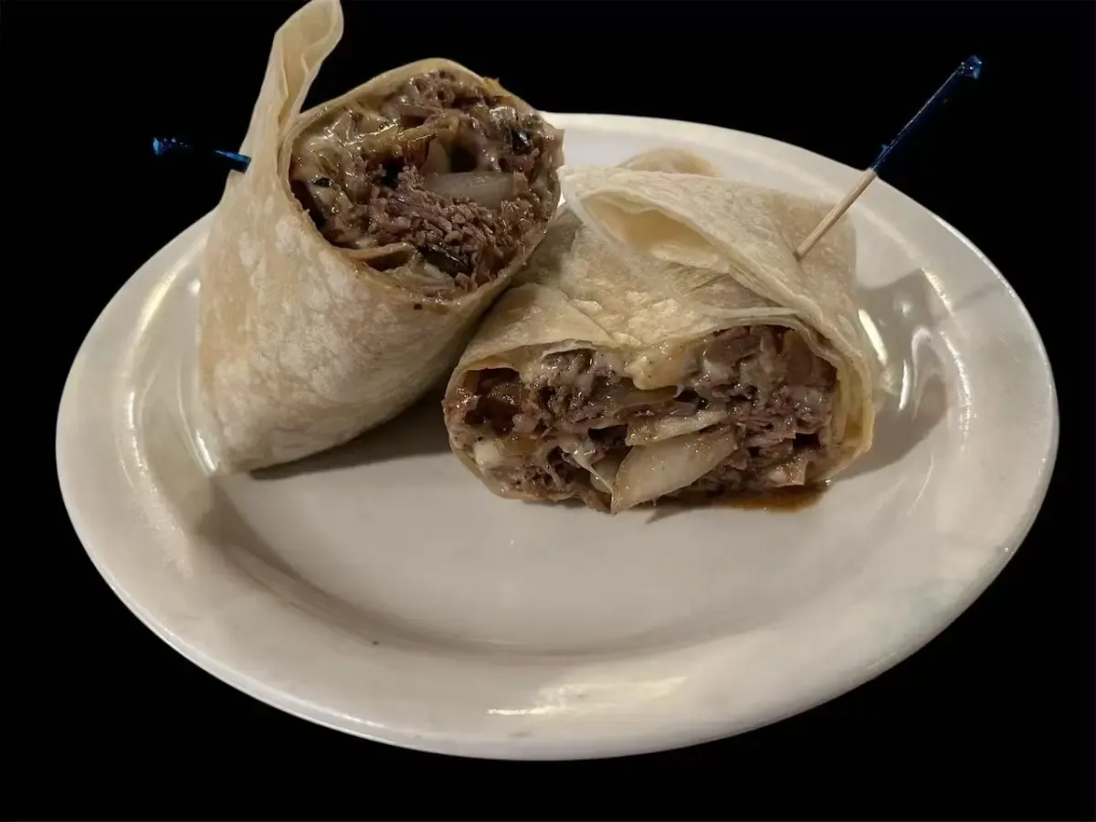 Roast beef wrap cut in half on a plate