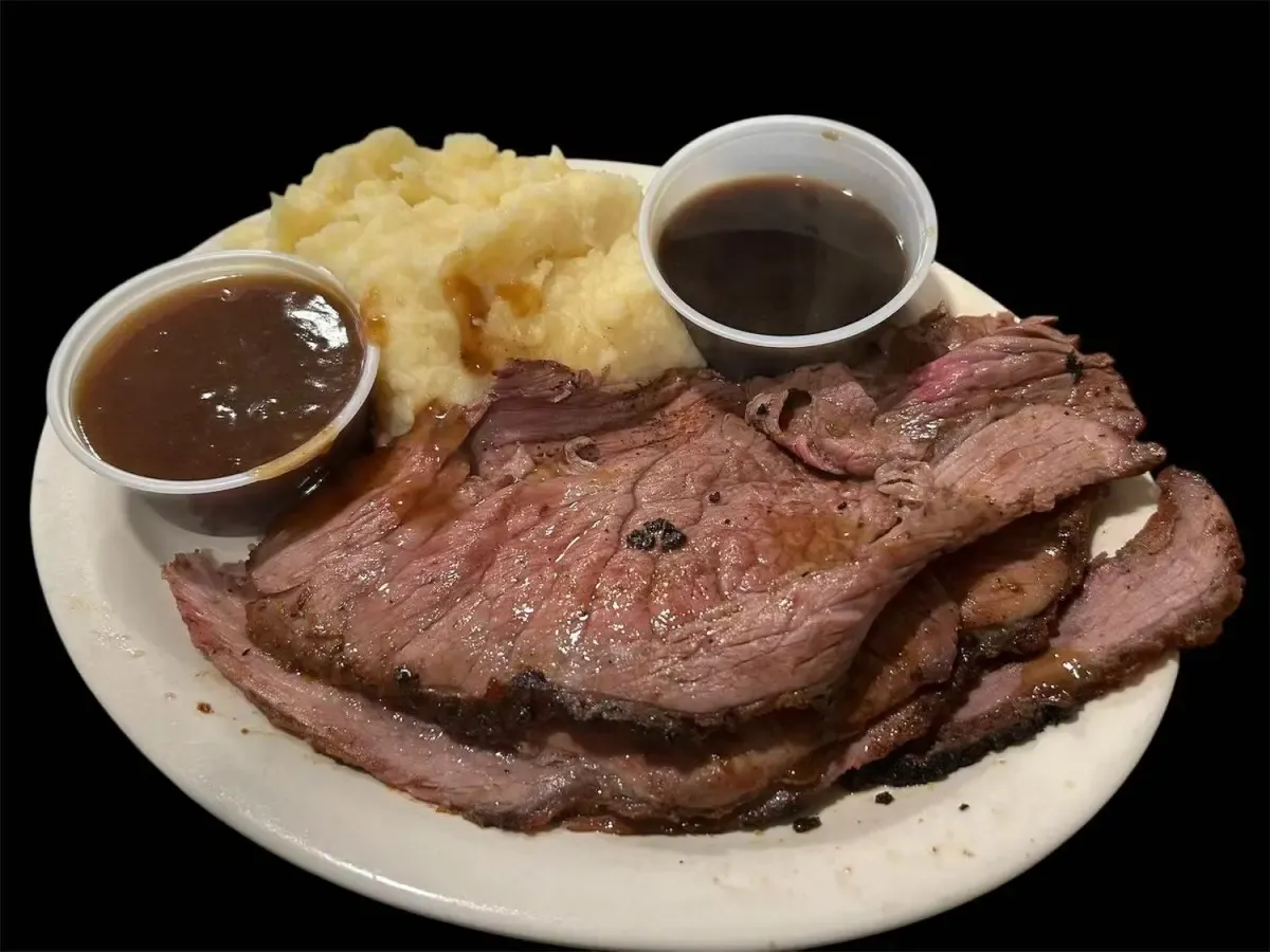 Sliced prime rib with mashed potatoes and two cups of au jus